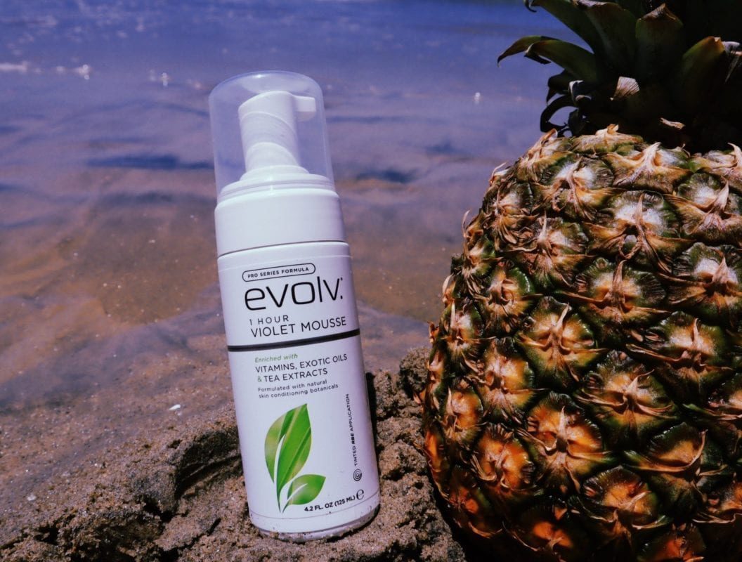 A bottle of Evolv Mousse tanning product. The bottle is white with a black pump dispenser and features the Evolv branding and product information on the label. The background is plain white, highlighting the product